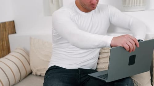 Caucasian male wearing white shirt opens his laptop. Working from home remote from office.