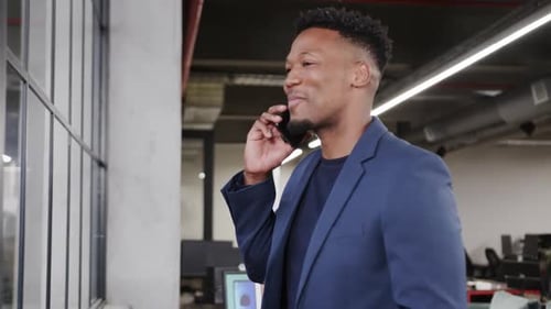 Happy african american male creative talking on smartphone at casual office, in slow motion