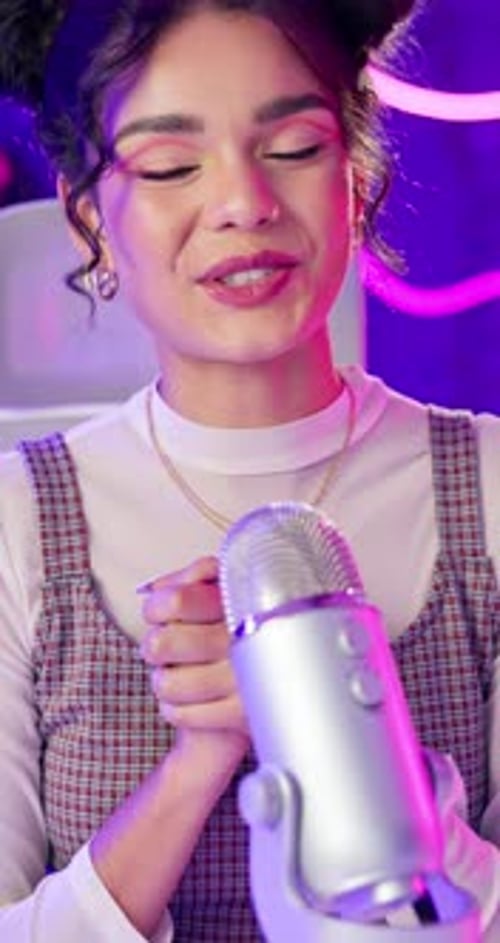 Young Woman Recording Into Microphone At Home