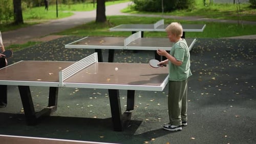 Child and Adult Play Ping Pong in Park
