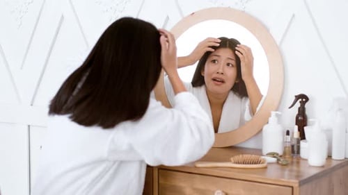 Worried Woman Examining Her Hair in Mirror