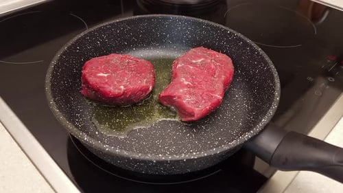 Raw Steaks Sizzling in Pan with Oil