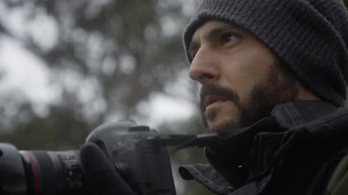 Bearded man taking picture with camera in nature