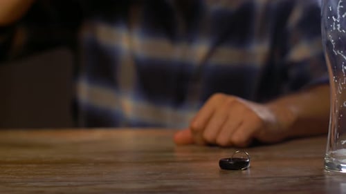 Man drinks beer with car keys on table