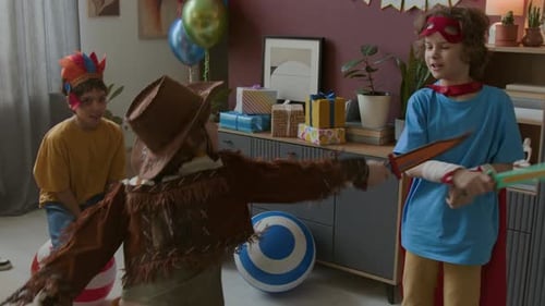 Grupo de crianças em trajes festivos brincando com brinquedos durante a festa de aniversário