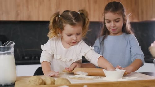 Dough work. Two little girls are preparing bakery at home.