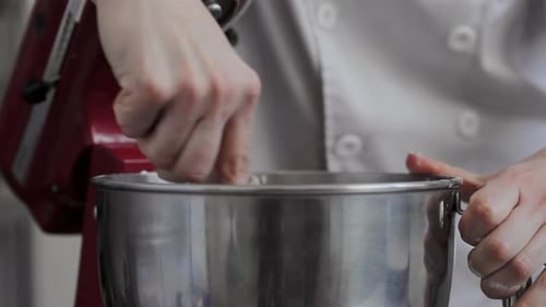 Chef takes metal bowl electric mixer out and mix cream dough at local bakery shop medium close-up sh