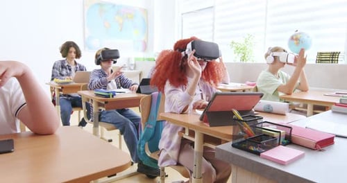 Interactive School Concept Kids in VR Headsets Sitting at Desks and Having Virtual Reality Learning
