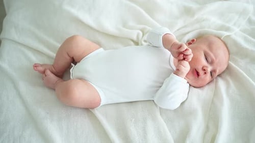 Adorable Infant Lying on White Blanket in Home