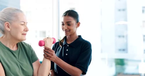 Physical Therapist Assists Senior Woman Lifting Dumbbell