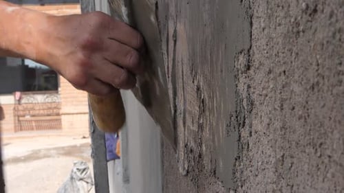 Construction worker plastering wall using concrete. Latino man placing cement on wall. Close up of m