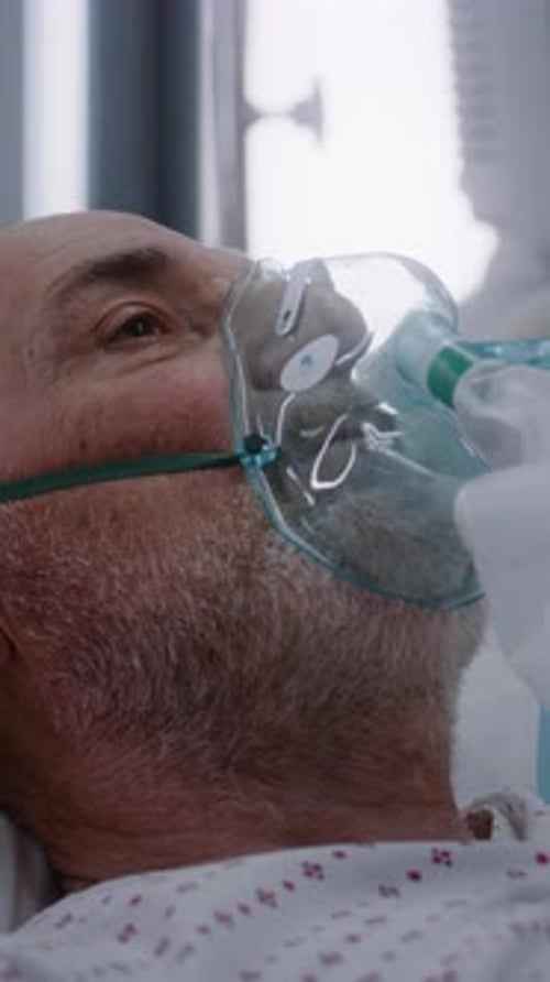 Senior Man Wearing Oxygen Mask in Hospital Bed