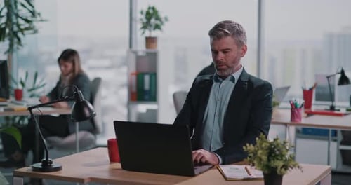Workers at Desks Typing on Computers in Modern Office
