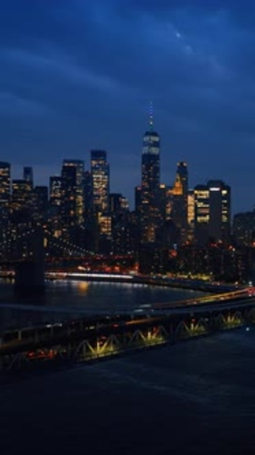 Impressive sight of night New York from the side of the river. Numerous cars ride by the bridges