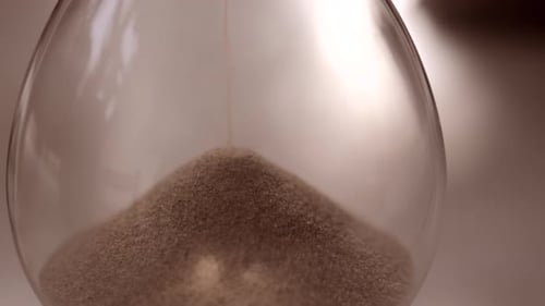 Hourglass sand falling in slow motion close up