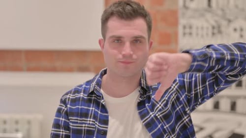 Retrato de un joven casual con los pulgares hacia abajo