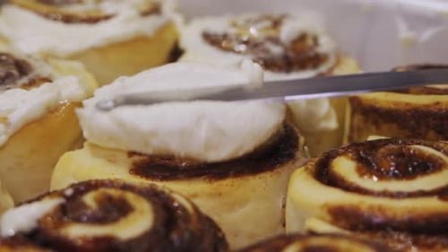 Frosting Freshly Baked Cinnamon Rolls With Cream Cheese Icing. close up