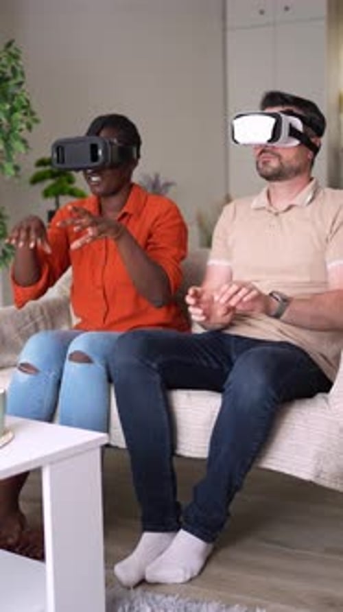 Couple wearing VR headsets sitting on sofa