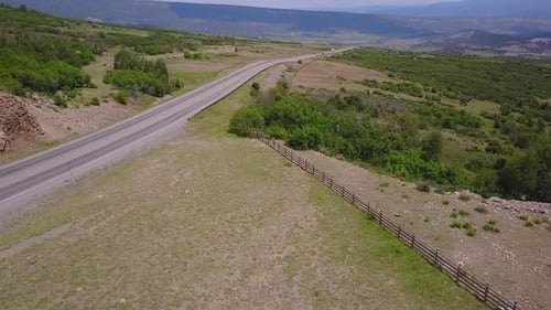Aerial: Dallas Divide Highway on gentle hillside on clear, sunny day