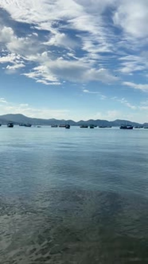 Fishing boats float on tranquil Cartagena bay with distant mountains under a blue sky