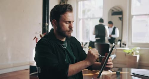 Man Works with Stylus on Tablet at Desk