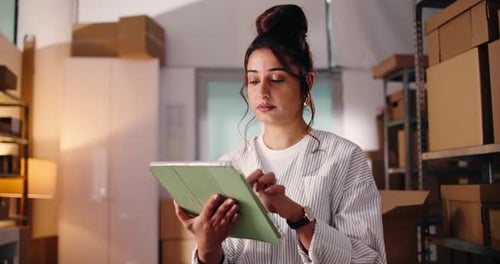 Woman Using Tablet in Warehouse Full of Boxes