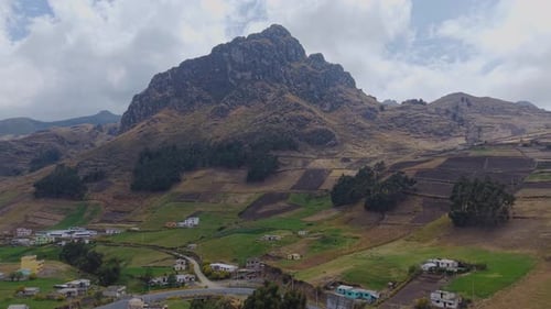 Aerial View Revealing Rock Formation Towering Over Patchwork Farmlands and Small Rural Settlement