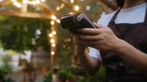 Unrecognizable Employee Handing Terminal to Buyer with Card