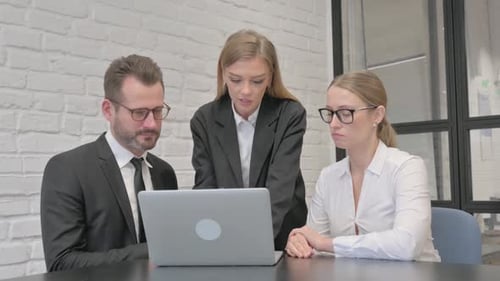 Colleagues Collaborate on Laptop in Bright Office