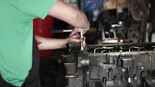 Mechanic Repairs Large Diesel Engine with Socket Wrench