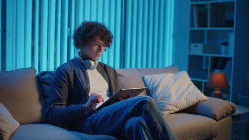 Young Man Using Tablet Device on Couch at Home