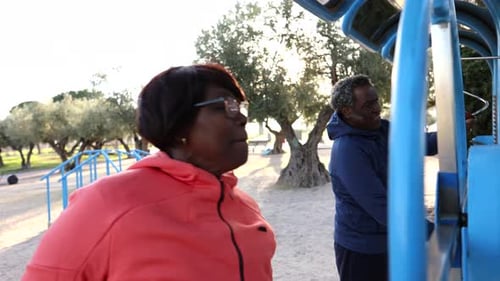 Senior Woman Observing Partner's Exercise at Outdoor Fitness Park