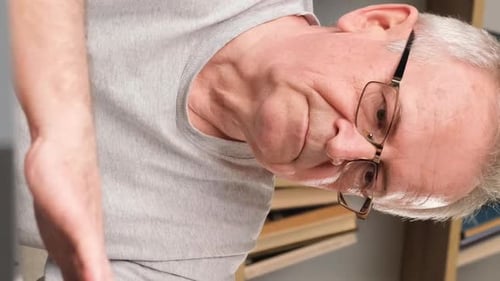 Senior Man Rubs Temples Wearing Glasses