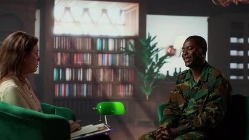 Man in Camouflage Uniform Interviewed by Woman Indoors