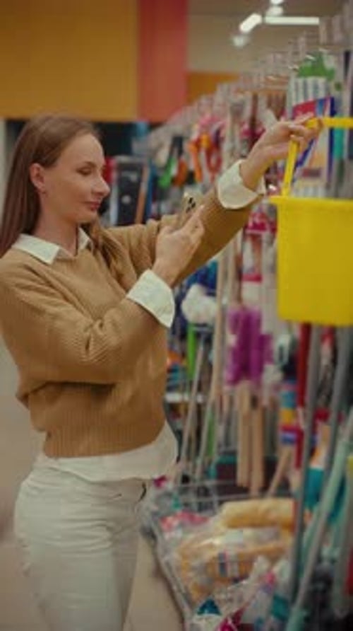Woman Shopping for Household Items in a Local Store Using a Smartphone for Scanning Products