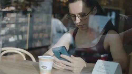 Close Up of Woman Holding Cell Telephone Watching Video on Mobile Phone During Coffee Break View