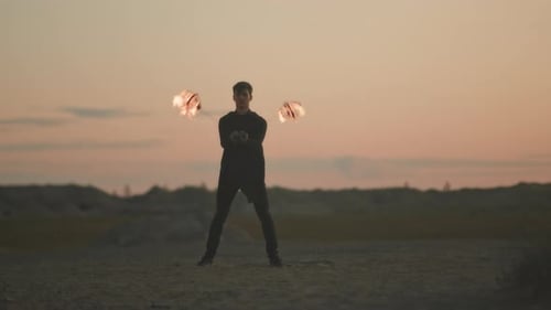 Man Juggling with Fire on Sandy Beach at Sunset