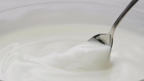 White Creamy Sauce Texture Closeup Dip a Spoon Into White Yogurt Macro Dairy Products Concept