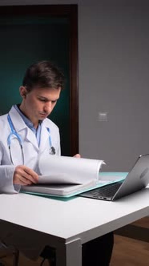 Vidéo verticale, médecin de sexe masculin concentré en blouse médicale blanche examinant les documents des patients et les utilisant