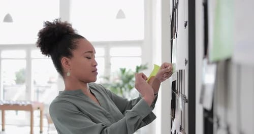 African American businesswoman putting sticky note on board
