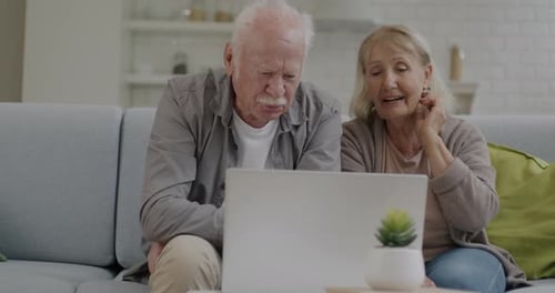 Senior Couple Video Chatting on Laptop at Home