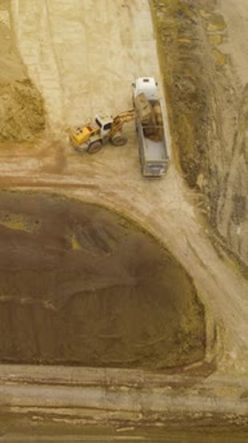 Aerial View Of Excavator Loading Sand Into Dump Truck At Construction Site