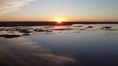 Crane drone view at sunset above a lake, wetlands with a river in the background. Taken at golden ho