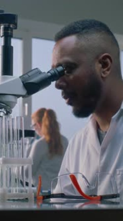 Scientist Looking Through Microscope in Bright Lab