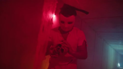 Axe man with mask holding item in dark tunnel