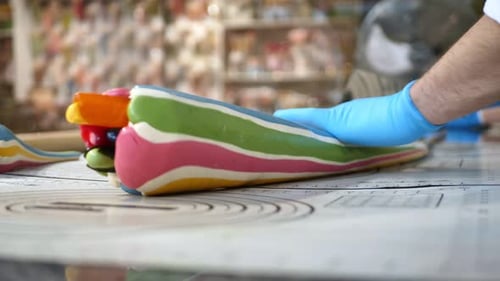 Closeup of the Chef's Hands Which Stretches Caramel Lollipops with a Spatula Pattern Candy