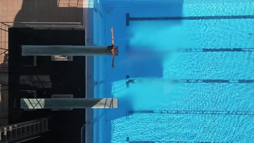 Drohnenaufnahmen, die einen Taucher in der Luft bei einem Tauchgang über einem klaren blauen Pool einfangen, mit atemberaubendem