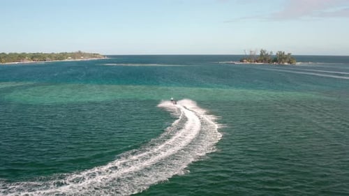 Speedboat Leaving Wake In The Blue Sea Sailing To The Island In Honduras. - aerial shot