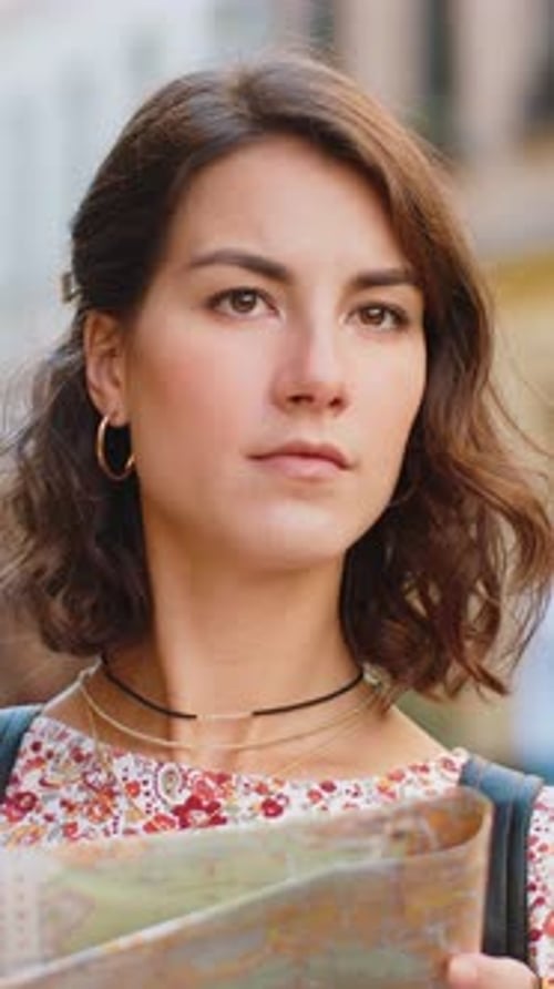 Woman Holding a Map in Urban Setting, Looking Up