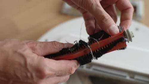 Hands Removing Hair from Robotic Vacuum Cleaner Brush